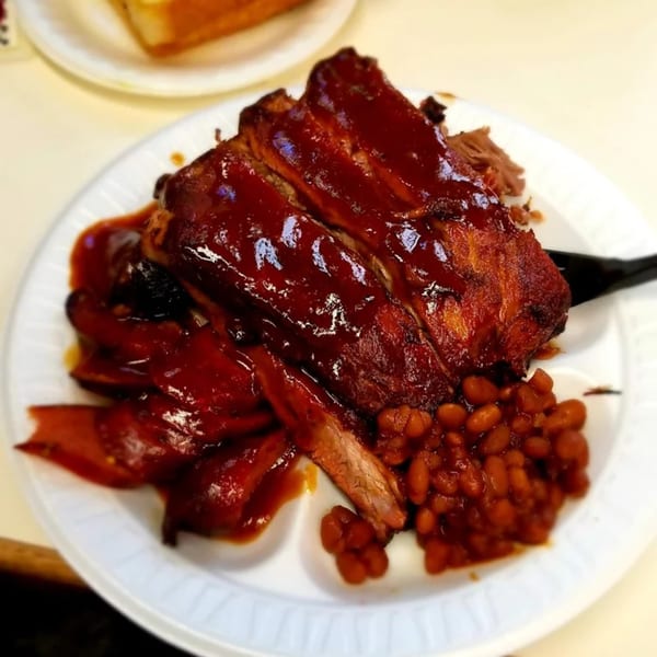 Roy's Hickory Pit BBQ ribs and sausage smothered in sauce, served with baked beans.