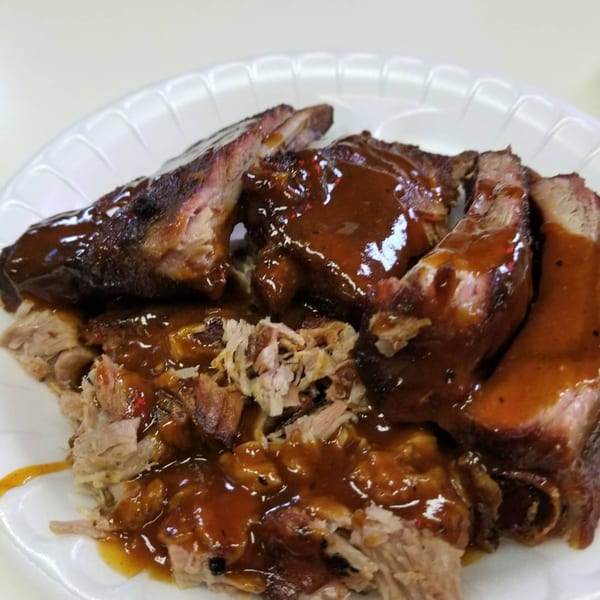 Roy's Hickory Pit BBQ plate with saucy ribs and pulled pork on a white plate.