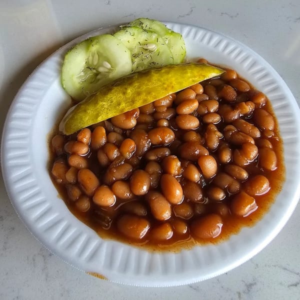 Roy's Hickory Pit BBQ baked beans with a pickle spear and cucumber slices on a white plate.