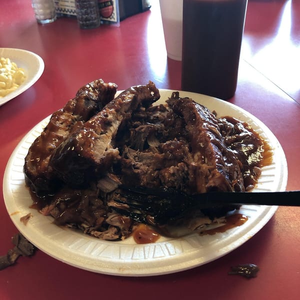 A plate of Roy's Hickory Pit BBQ ribs and pulled pork, covered in sauce, with mac and cheese.