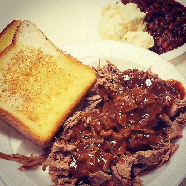 Roy's Hickory Pit BBQ pulled pork with sauce, toast, potato salad, and baked beans.